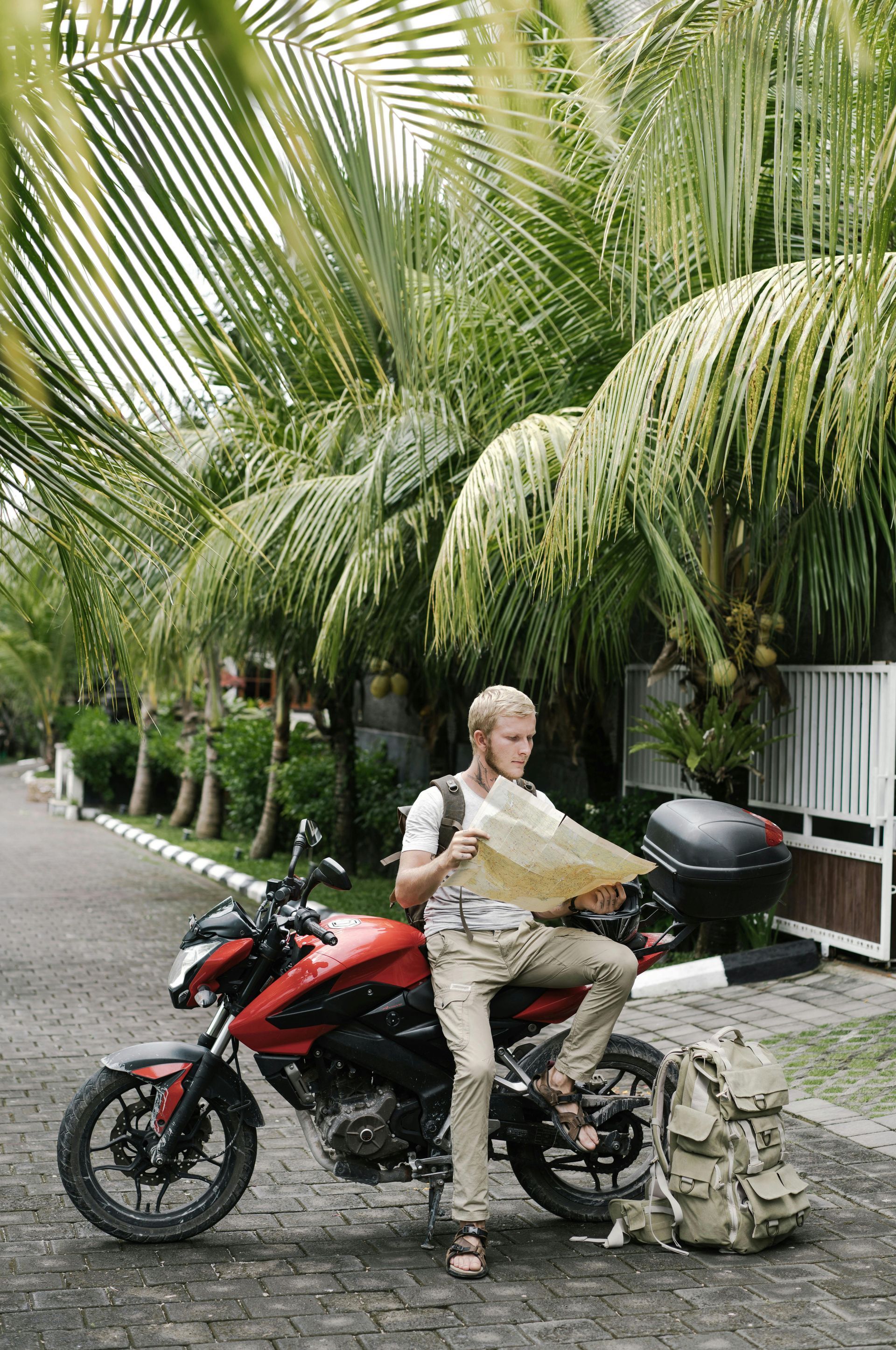 A man is sitting on a motorcycle looking at a map.