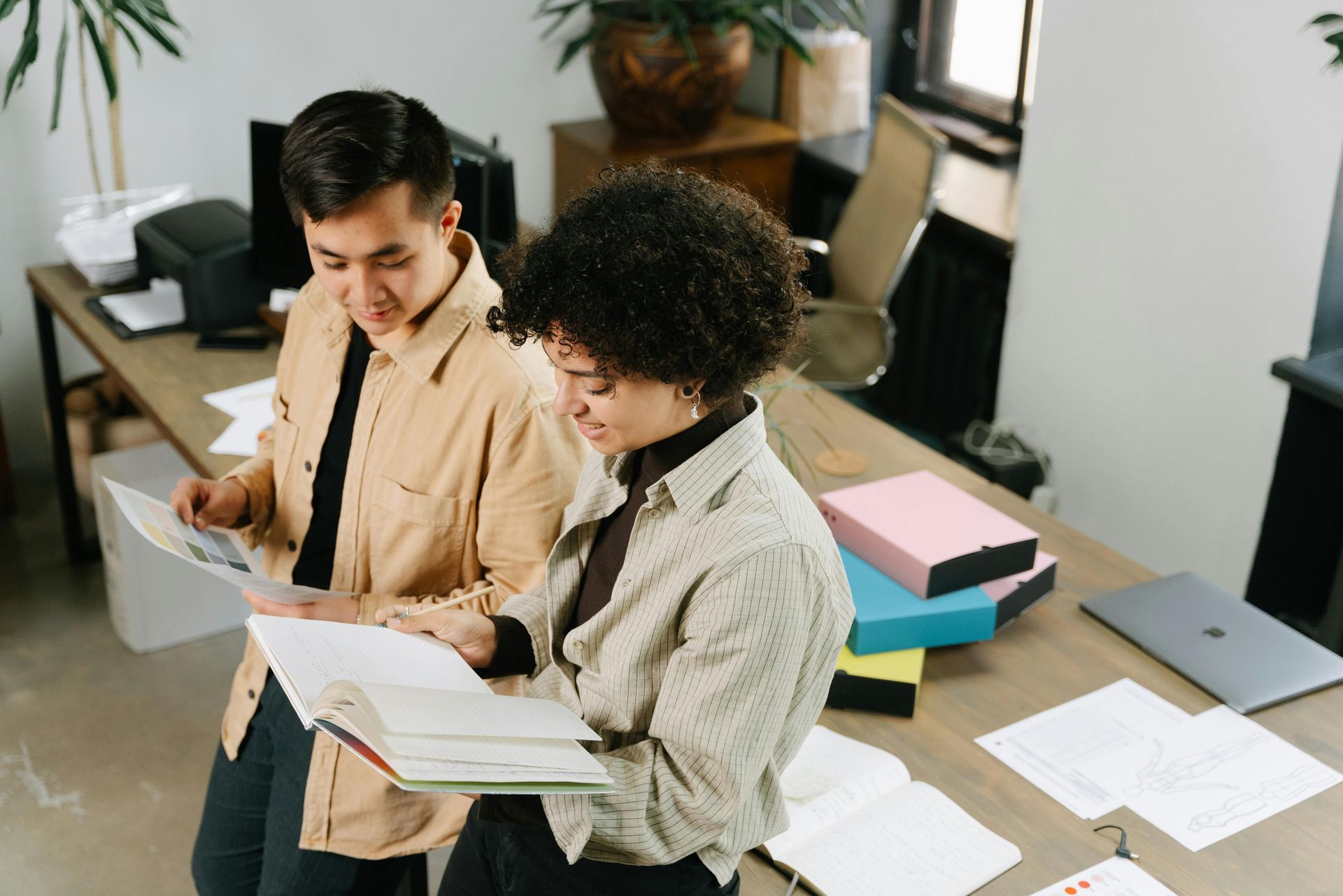 A man and a woman are looking at papers in an office.