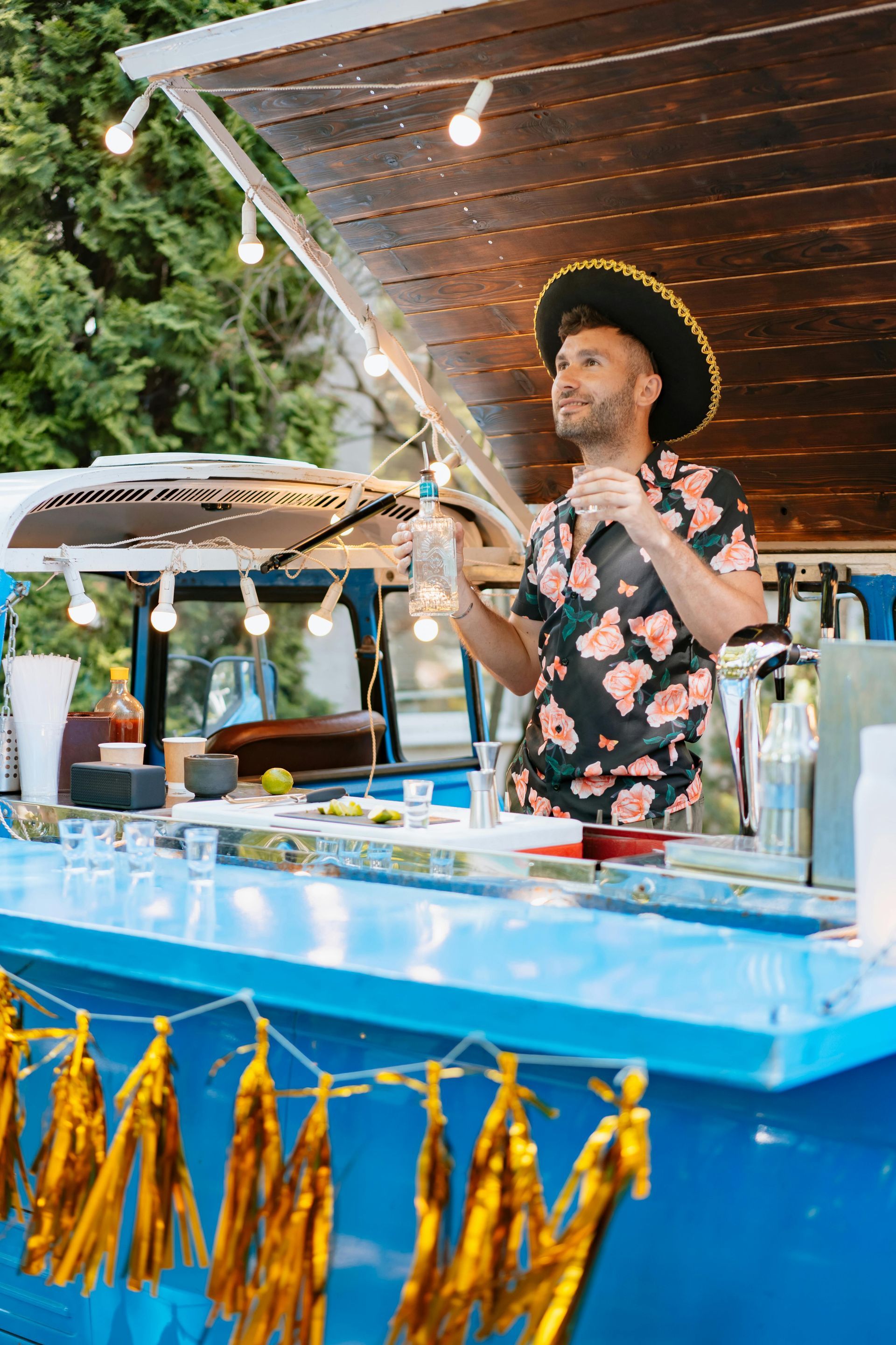 A man in a cowboy hat is standing behind a bar holding a microphone.