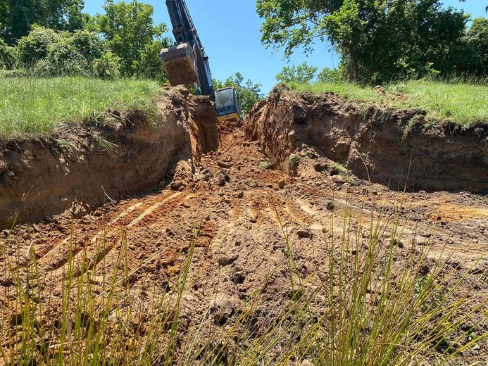 A bulldozer is digging a hole in the dirt in a field.