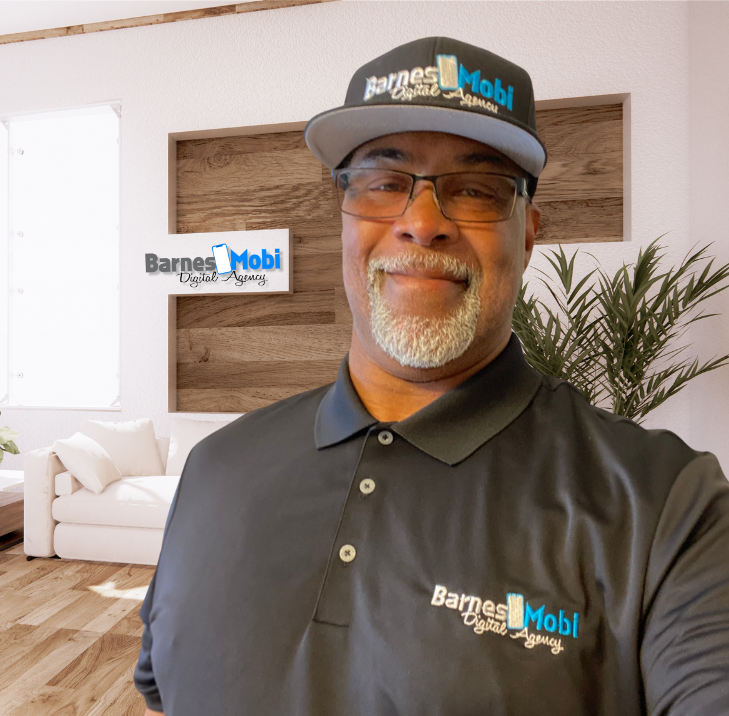 A man wearing a hat and glasses is standing in front of a wall that says barnes mobi digital agency