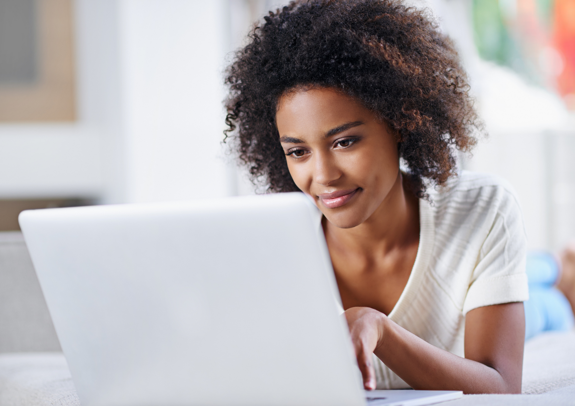 A woman is laying on a couch using a laptop computer.