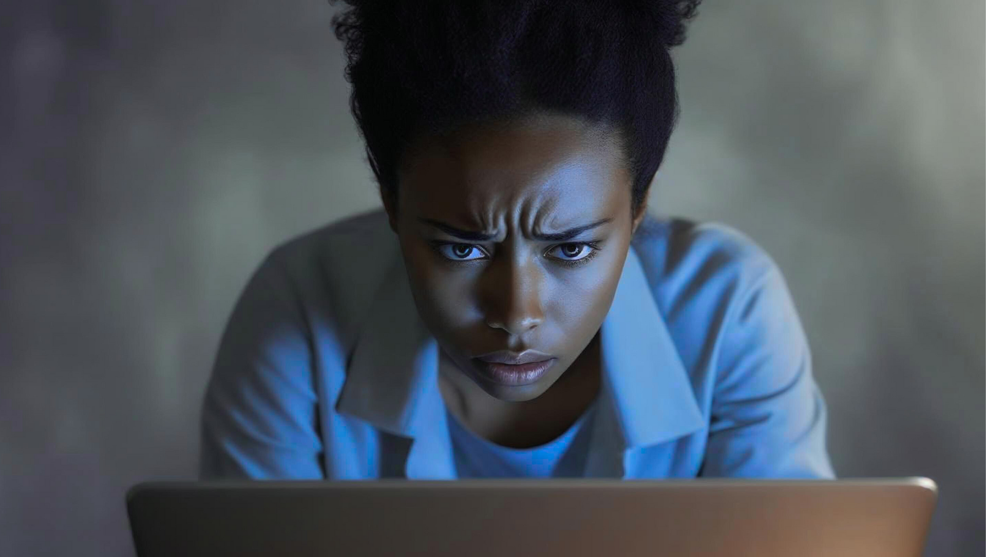A woman is sitting in front of a laptop computer at night.
