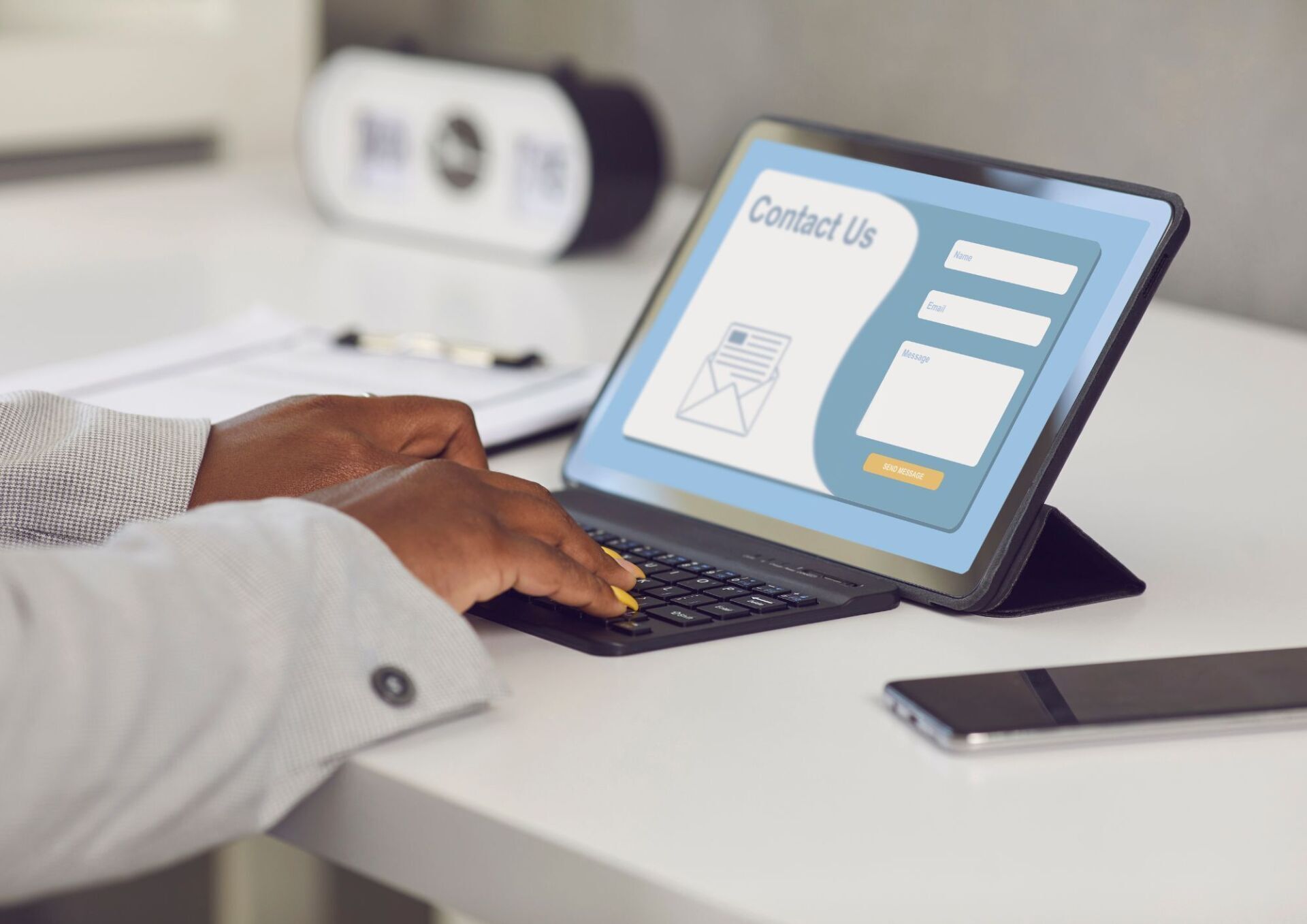 A person is typing on a laptop computer with a contact us page on the screen.