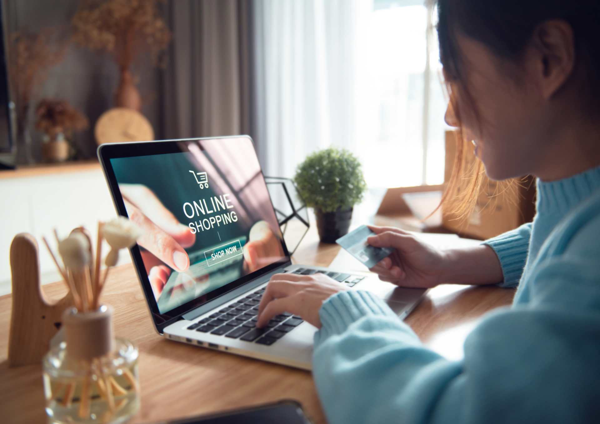 A woman is using a laptop computer while holding a credit card.