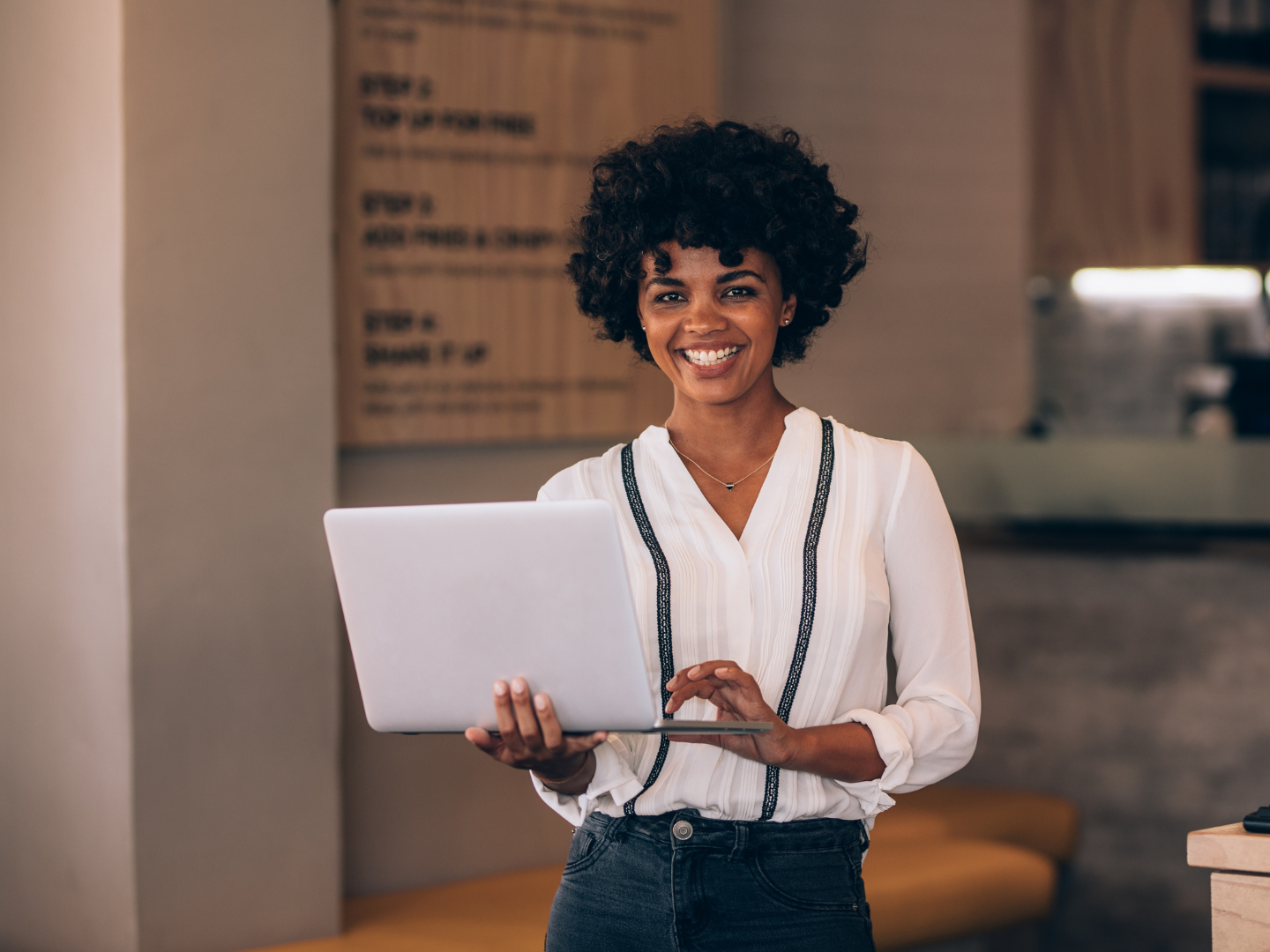 A woman is holding a laptop computer in her hands and smiling.