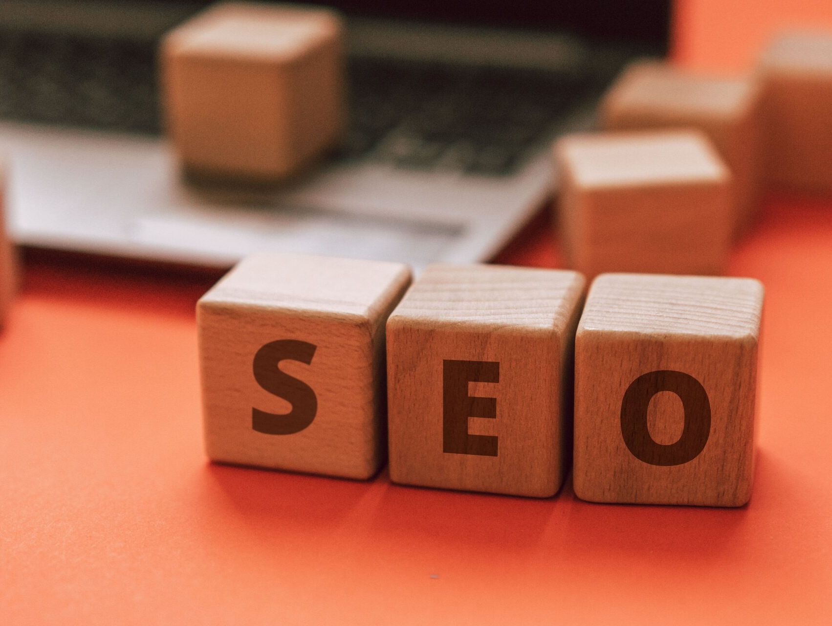 The word seo is written on wooden blocks in front of a laptop.