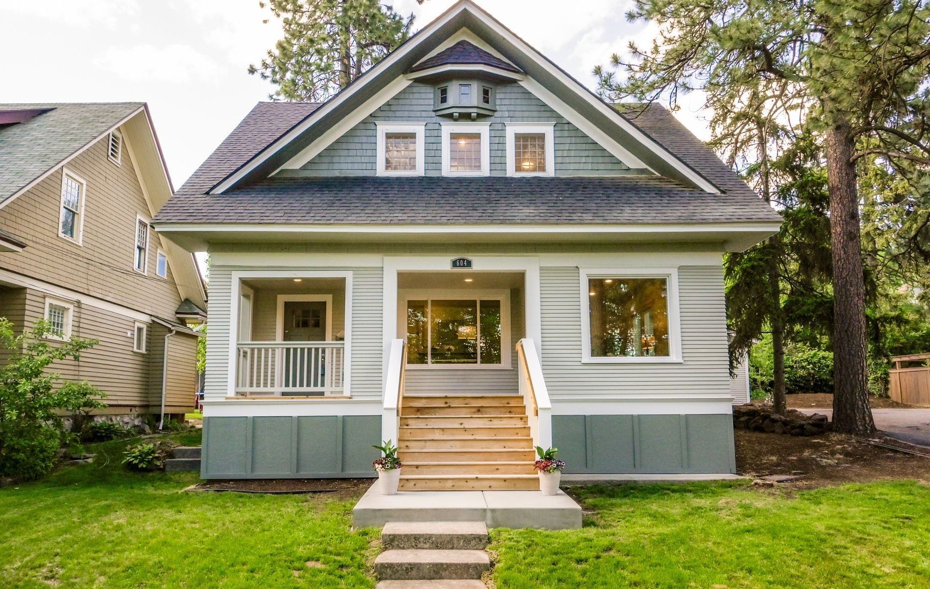 A small house with stairs leading up to it is sitting on top of a lush green lawn.