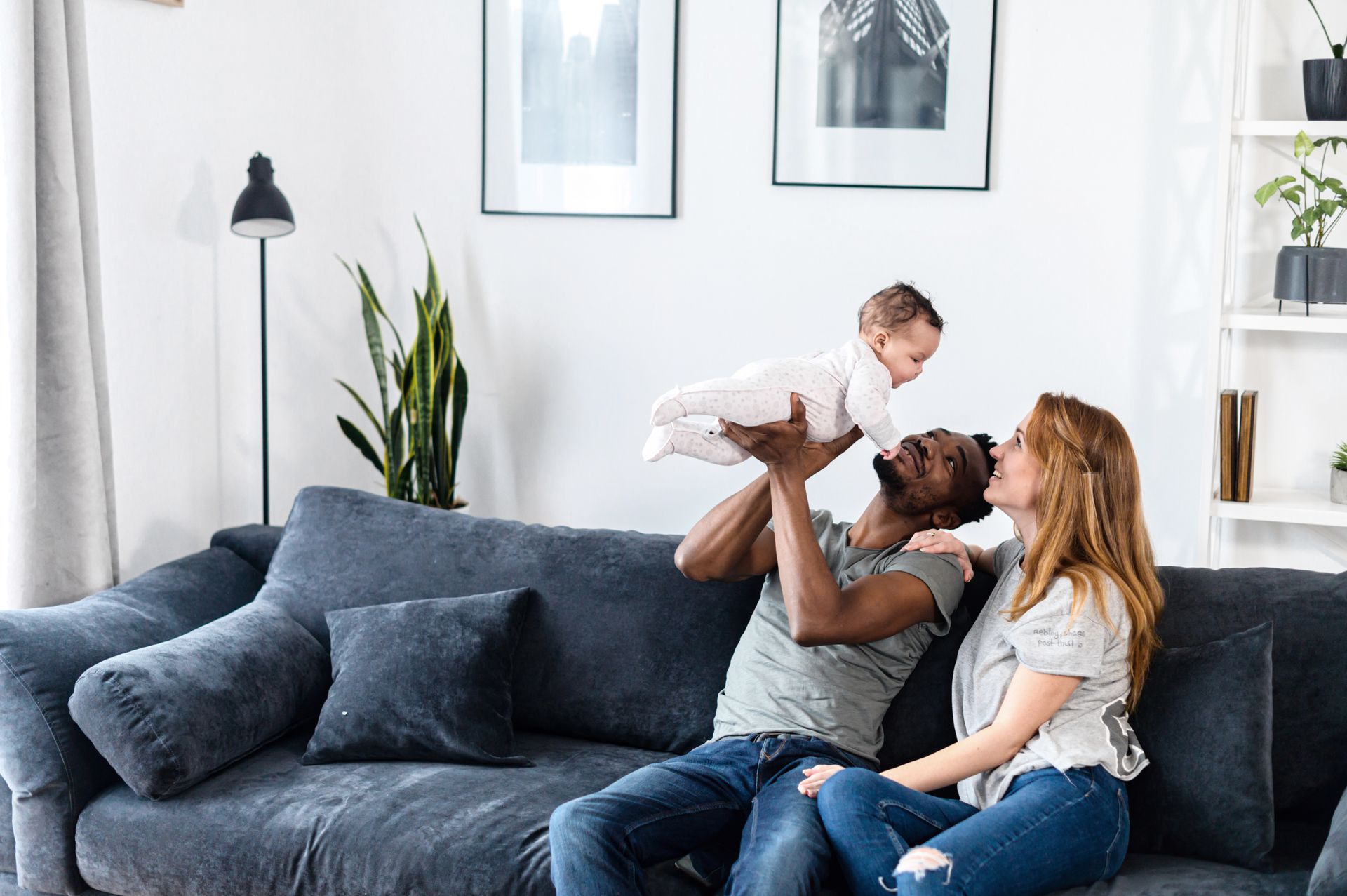 A man and a woman are sitting on a couch holding a baby.