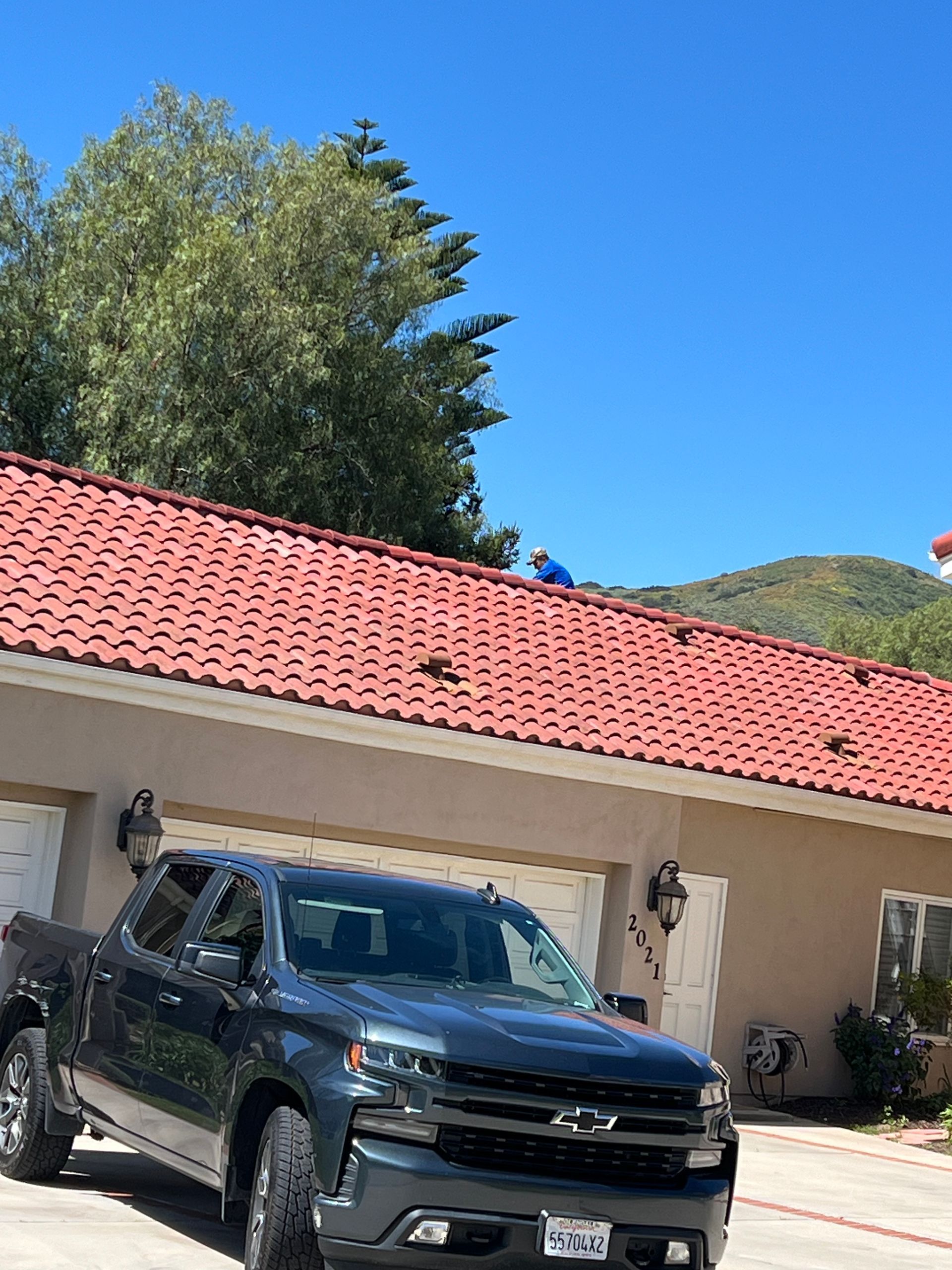 A man is standing on a ladder on the roof of a building.