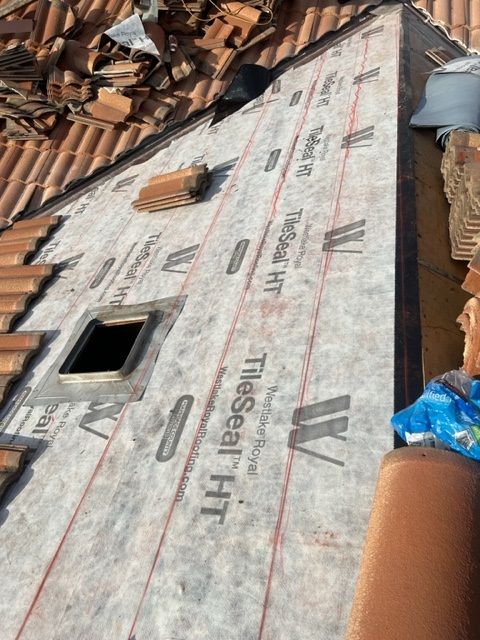 A person is standing on a tiled roof with a hole in it.
