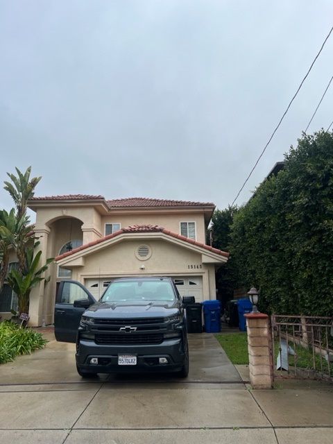 A black truck is parked in front of a large house