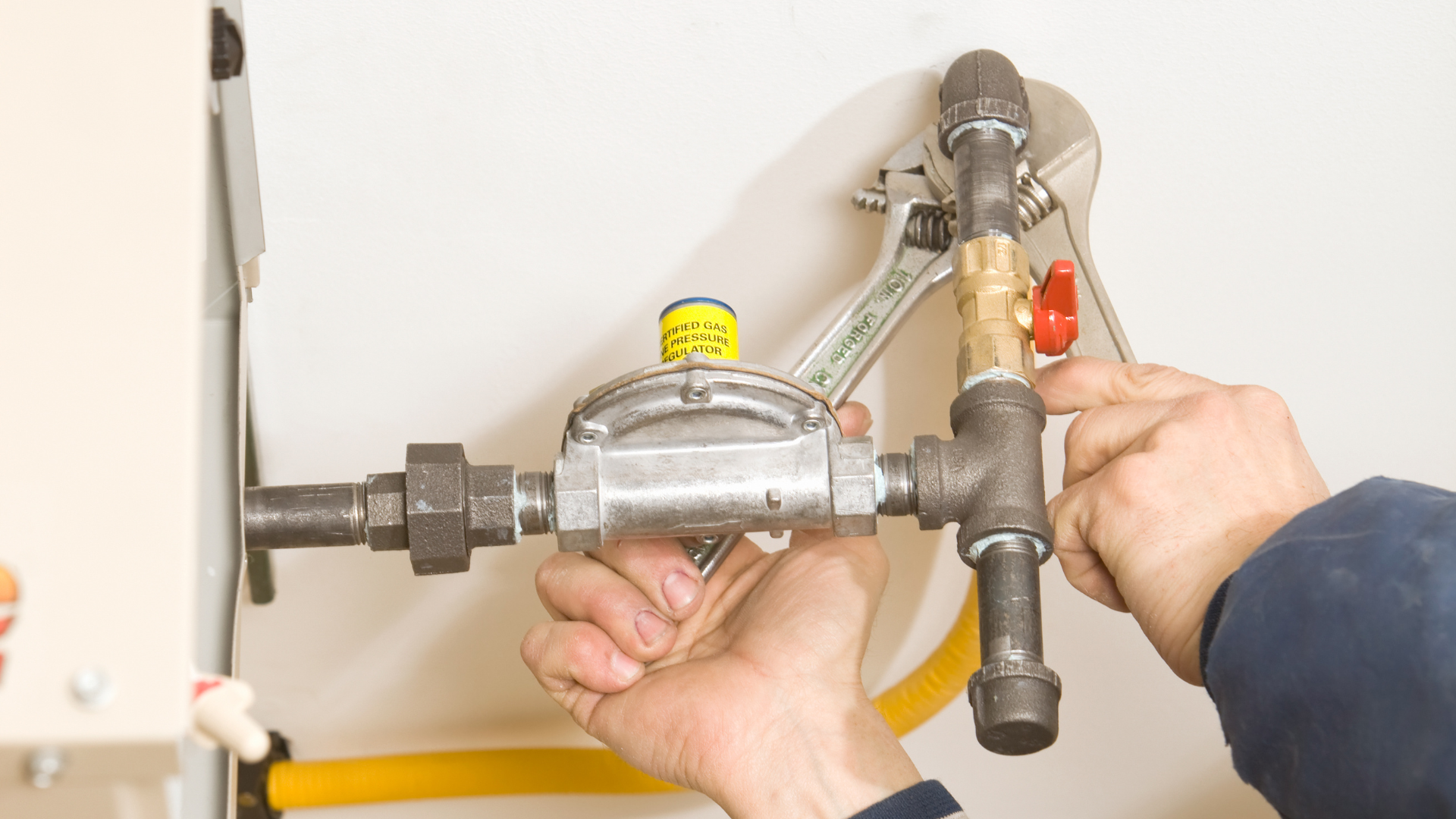 A person is fixing a gas valve with a wrench.