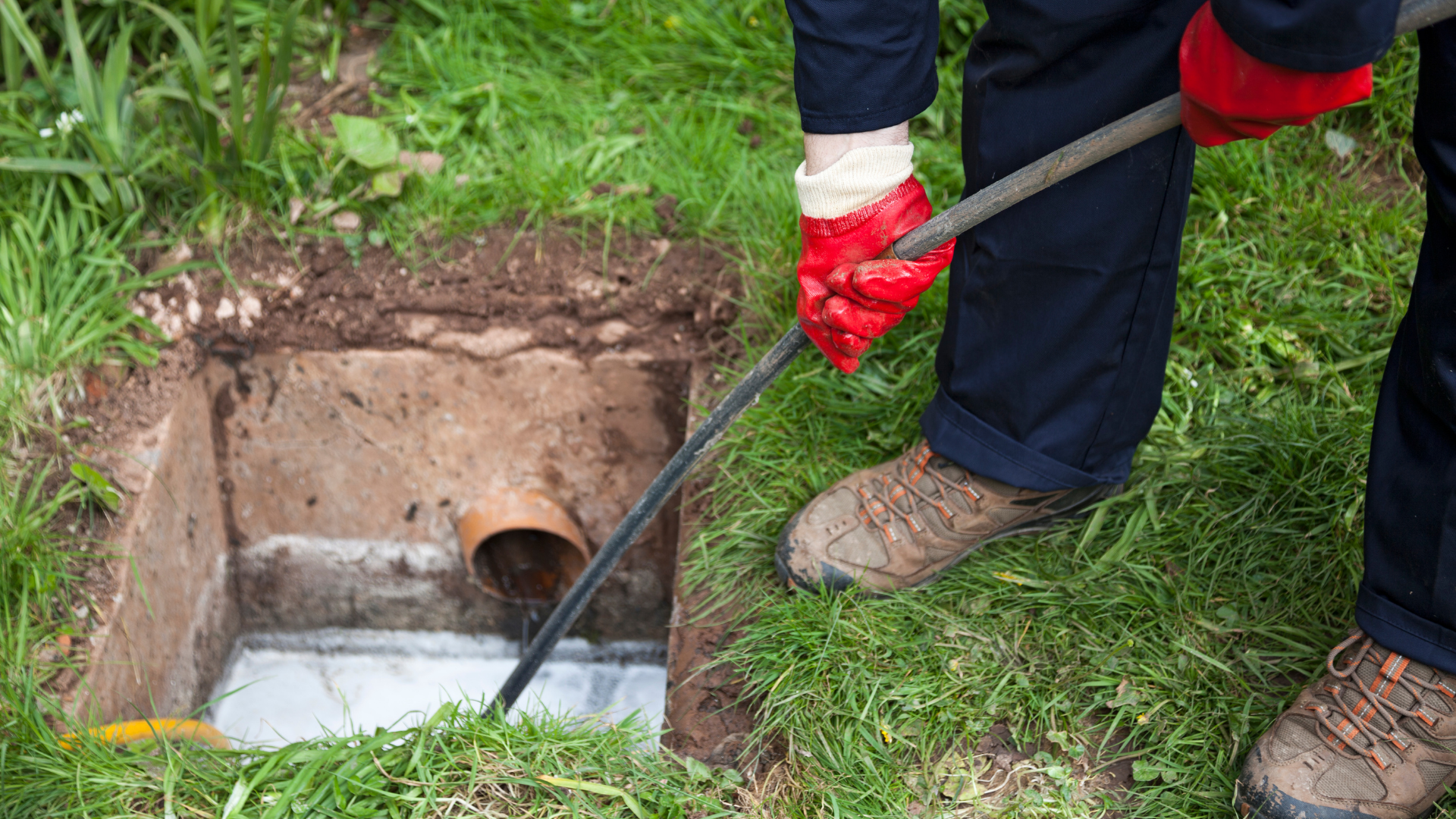 A person is cleaning a septic tank with a hose.
