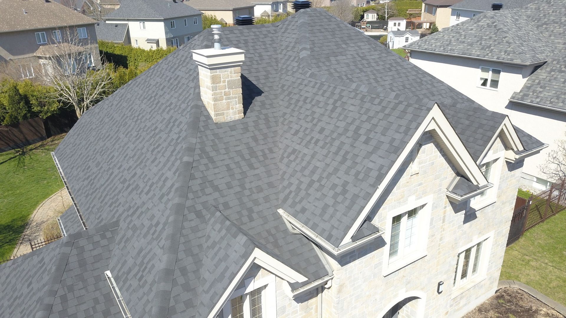 Une vue aérienne d'une maison avec un toit gris et une cheminée.