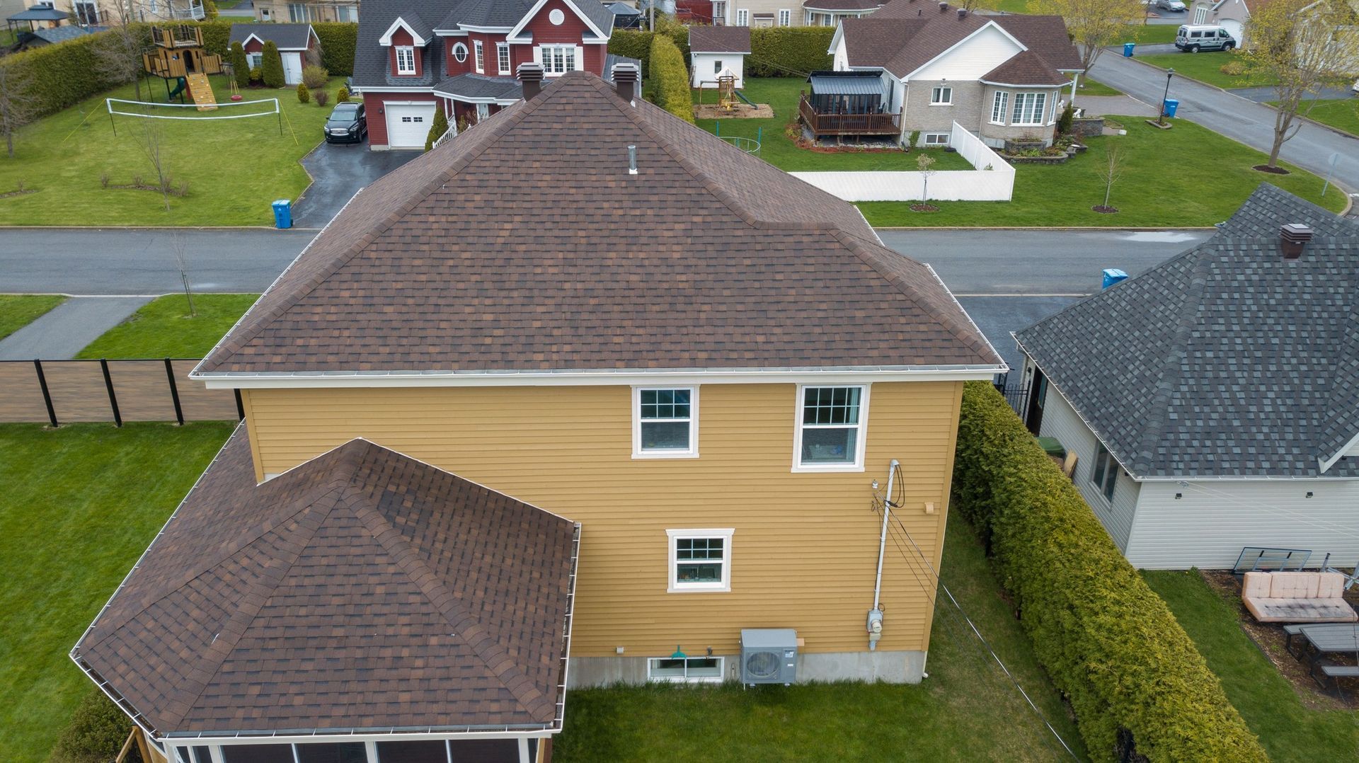 Une vue aérienne d'une maison avec un toit brun dans un quartier résidentiel.