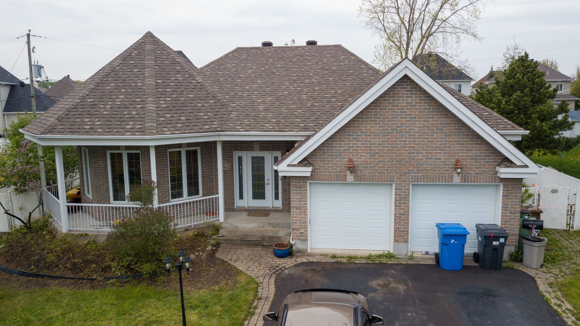 Une vue aérienne d'une maison en briques avec une voiture garée devant.