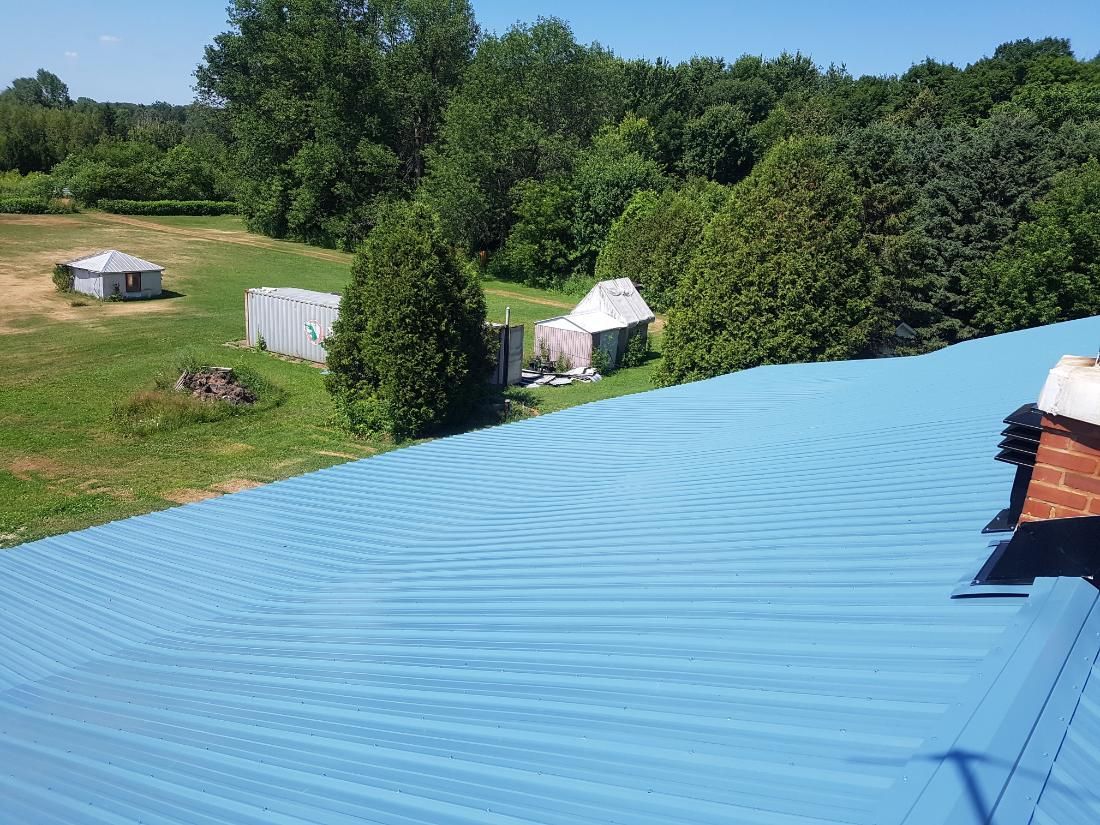 Un toit bleu avec une cheminée et des arbres en arrière-plan
