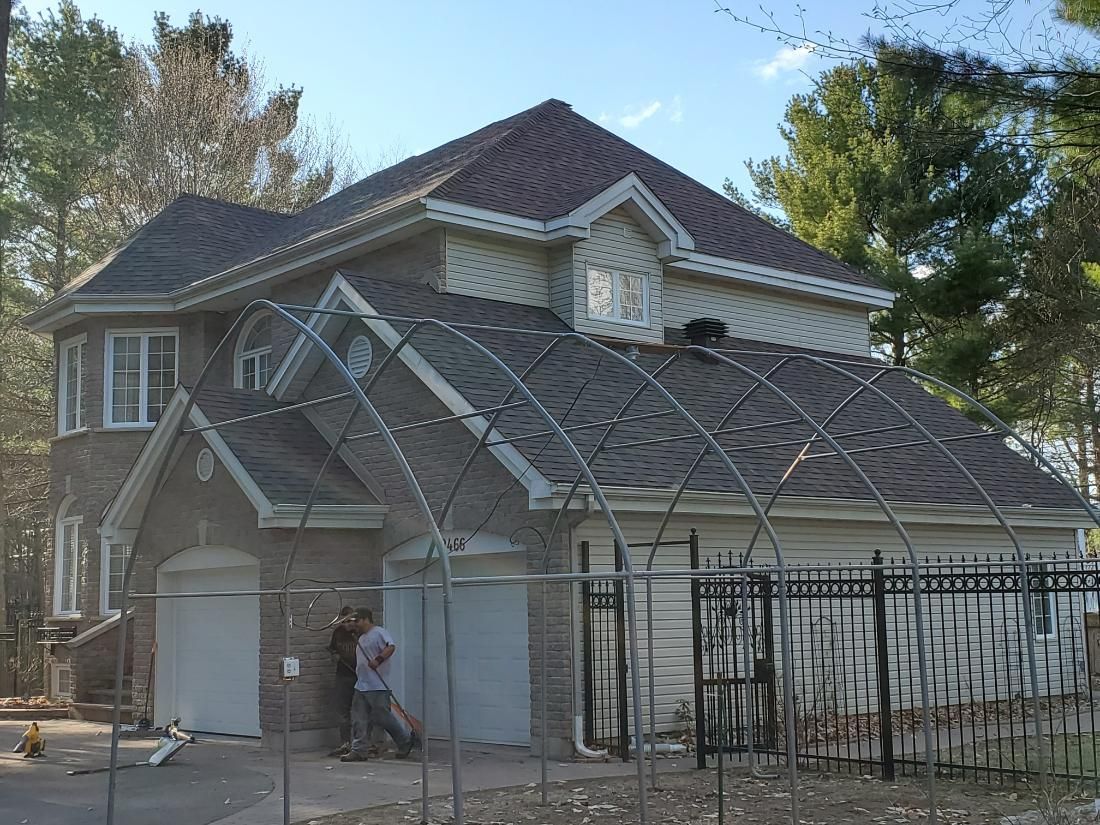 Un homme se tient devant une maison entourée d'une clôture.