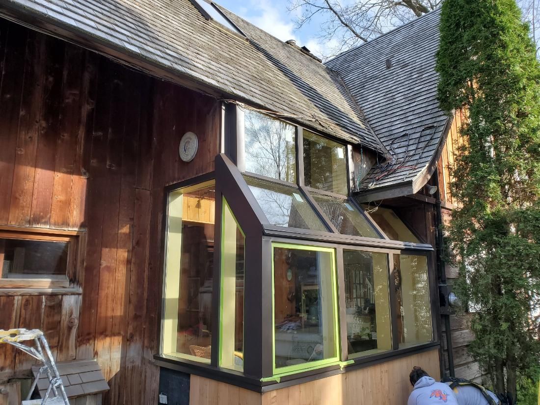 Une maison en bois avec une serre sur le côté.