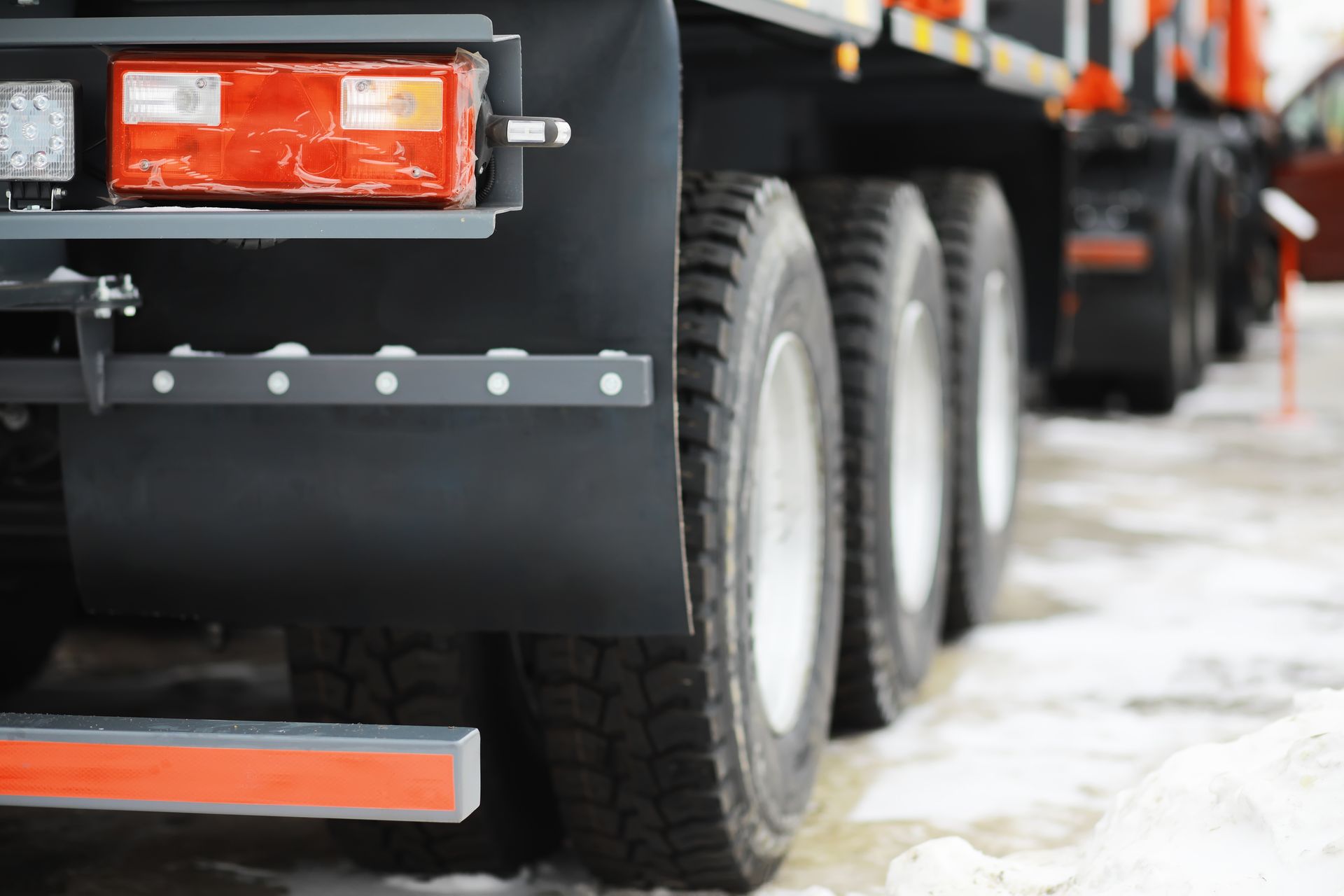 Black truck rear with wheels on snow, red lights.