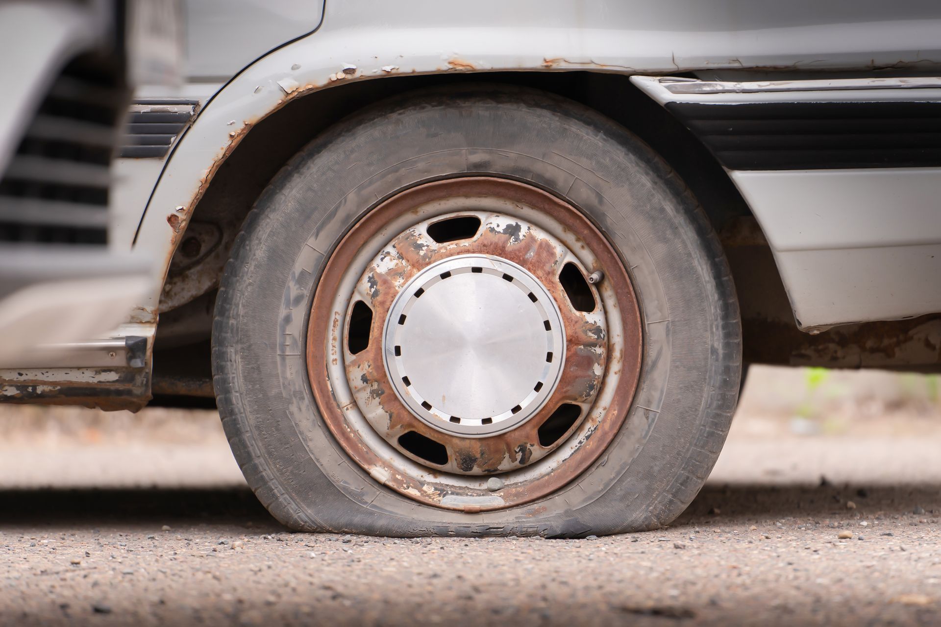 Flat tire on an old, rusty vehicle.