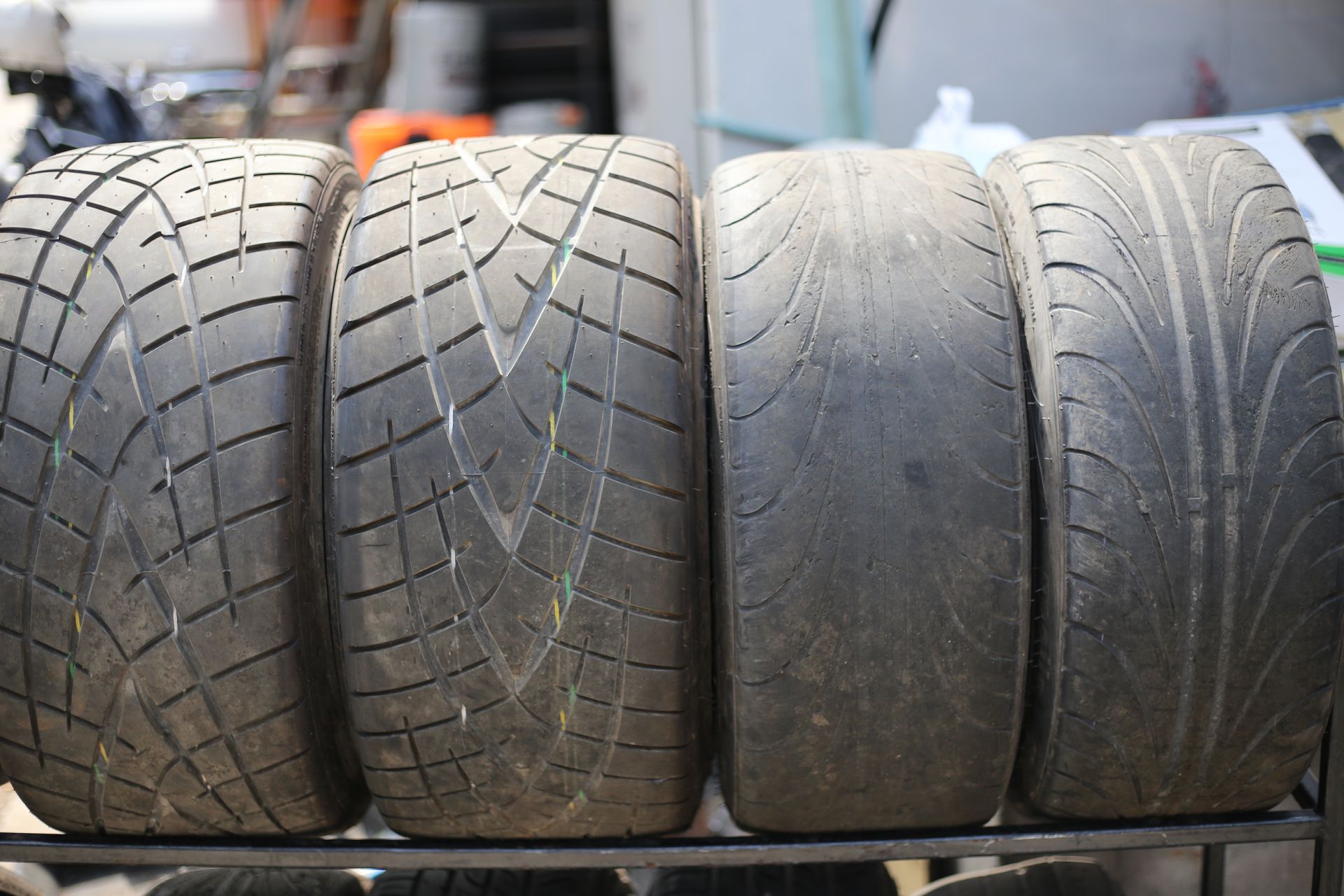 Four used car tires with varying tread wear, arranged side by side.
