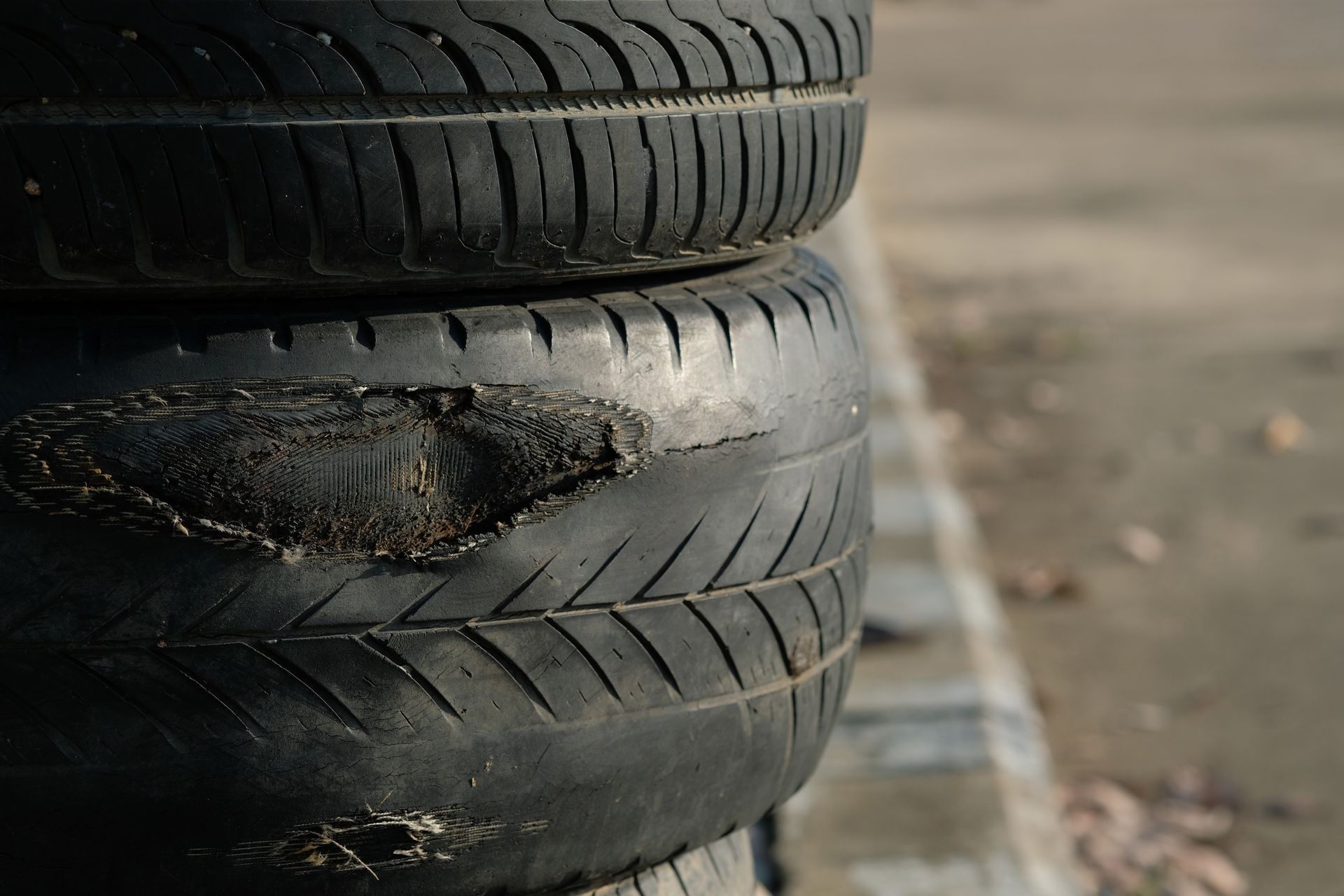 Stack of worn tires, one with significant damage.