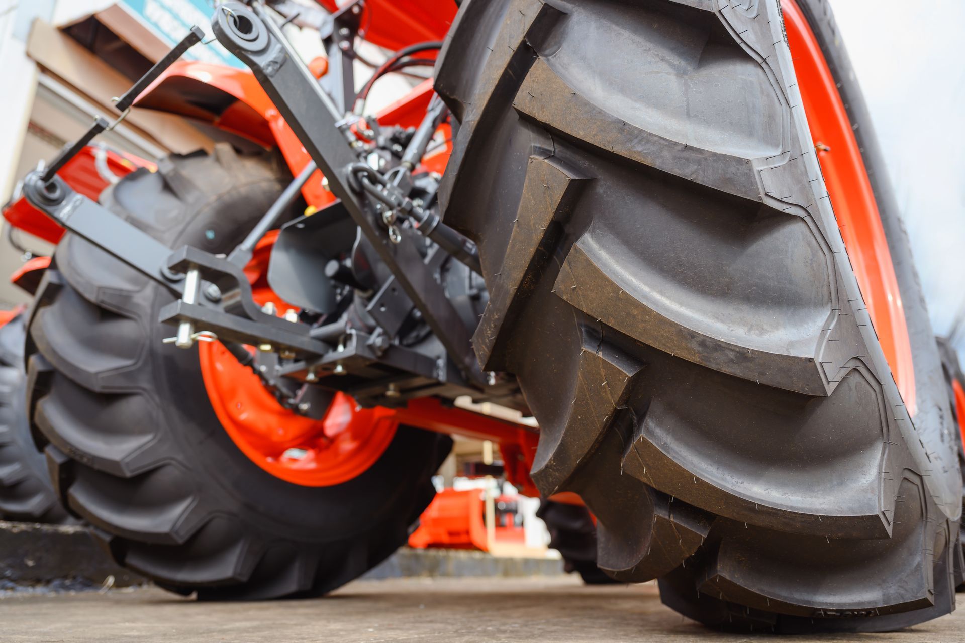 Close-up of a red tractor's rear tires, with thick treads and orange rims.