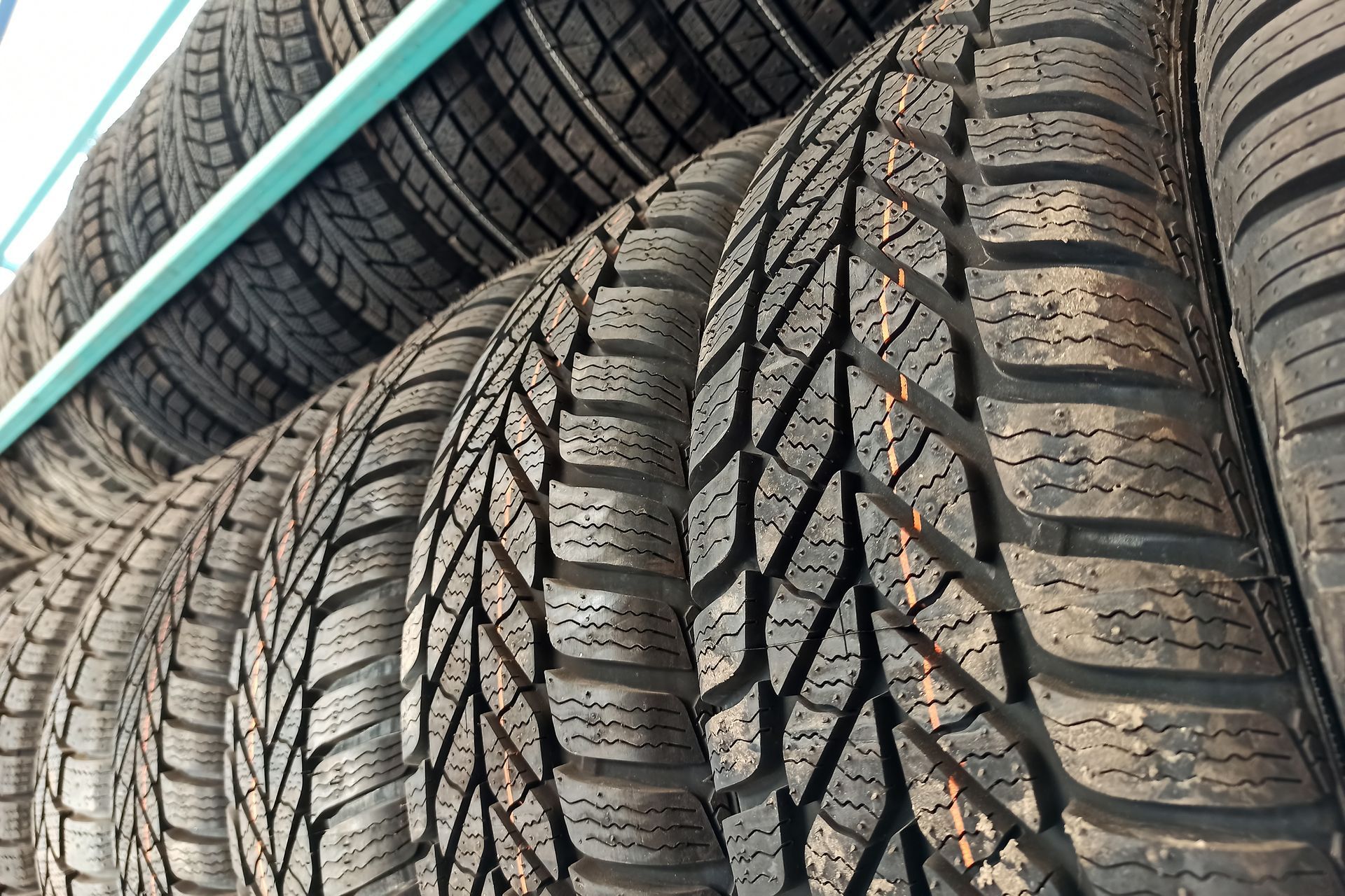 Row of new car tires on a shelf, showing tread patterns.