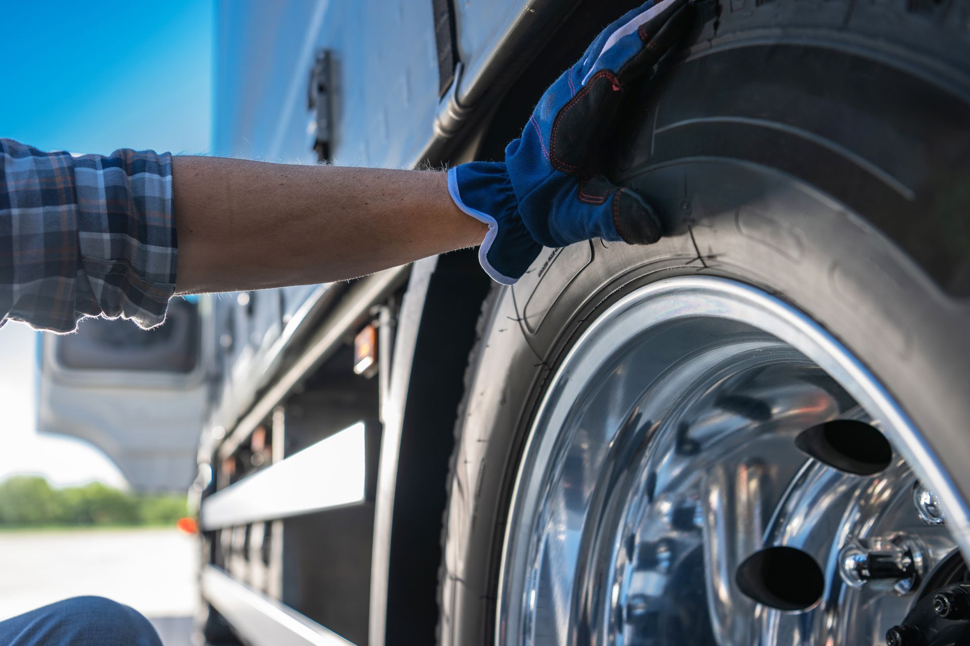 Person in blue gloves checking a semi-truck tire.