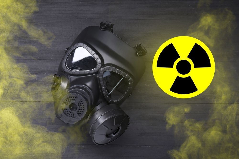 Black gas mask beside yellow radiation symbol on a dark smoky background