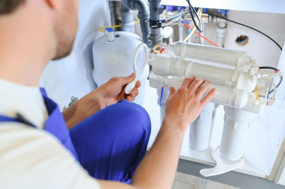 Technician adjusting a white water filtration system under a sink
