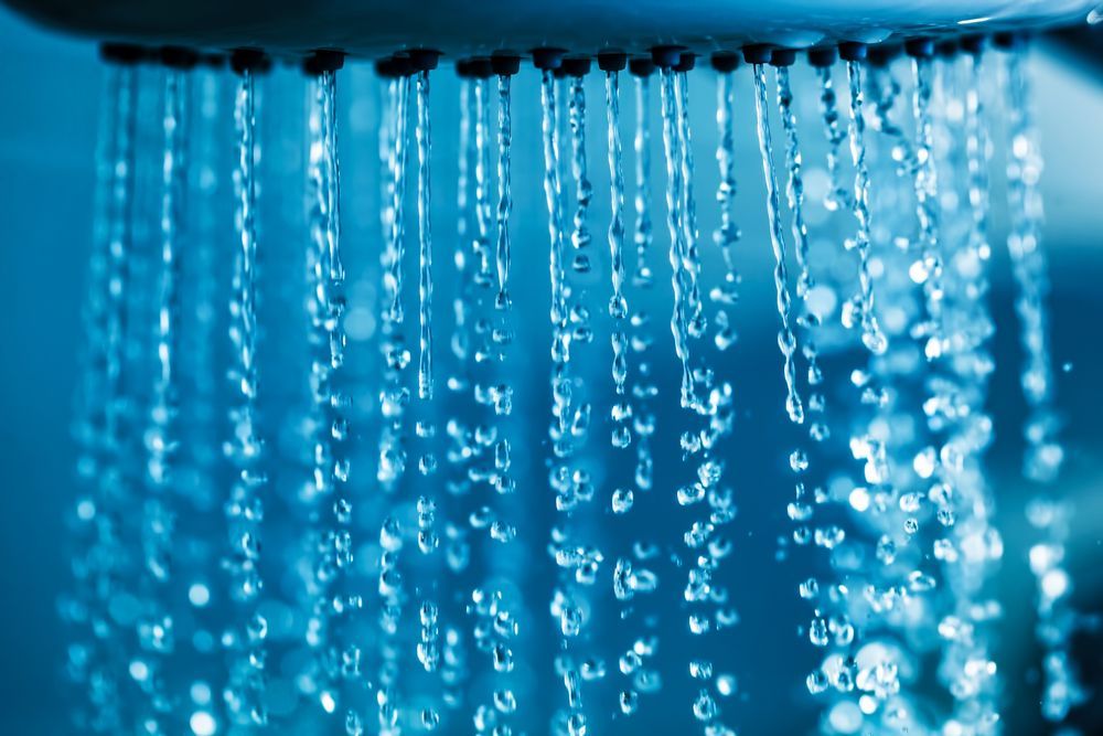 Blue water droplets hanging and falling against a blurred blue background