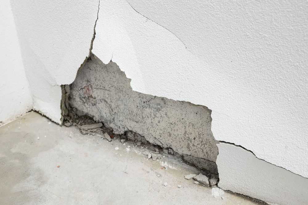 Damaged interior wall with crumbling plaster exposing concrete from hidden water leak in Rancho Cucamonga CA