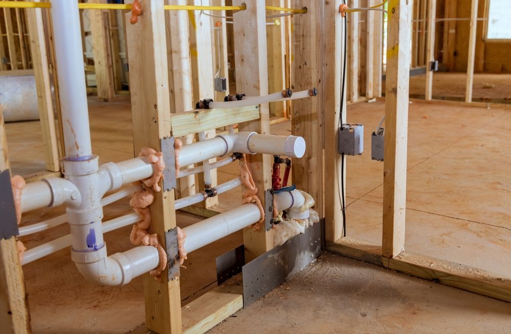 Exposed plumbing pipes and valves in unfinished wood-framed construction interior