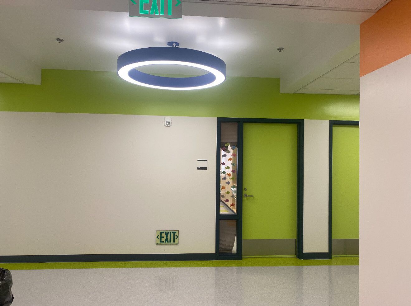 Hallway with white walls, green trim, and a circular light fixture. A green door is visible.