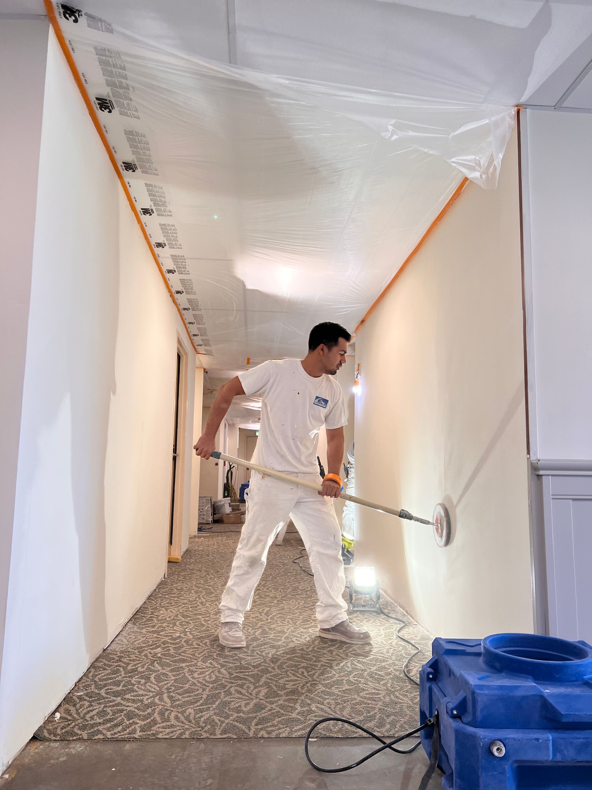A man is painting a wall in a hallway