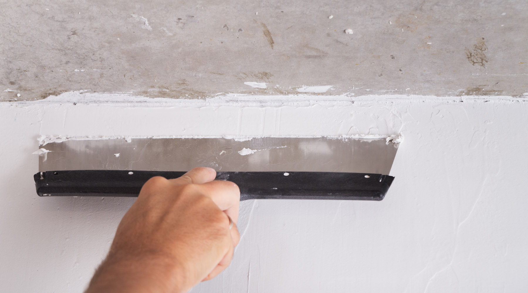 A person is plastering a wall with a spatula.