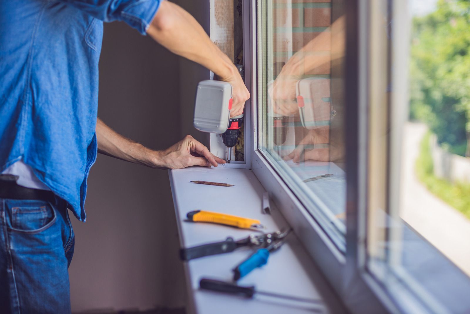 A man is installing a window on a window sill.