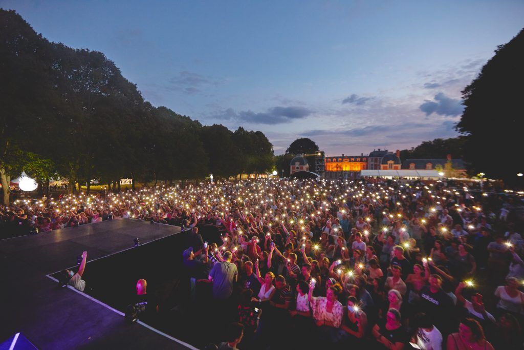 Une grande foule de personnes tiennent leurs téléphones en l'air lors d'un concert.