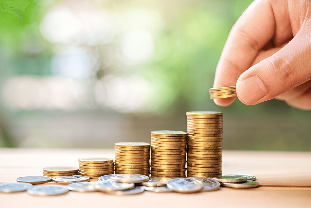 A person is stacking coins on top of each other on a table.