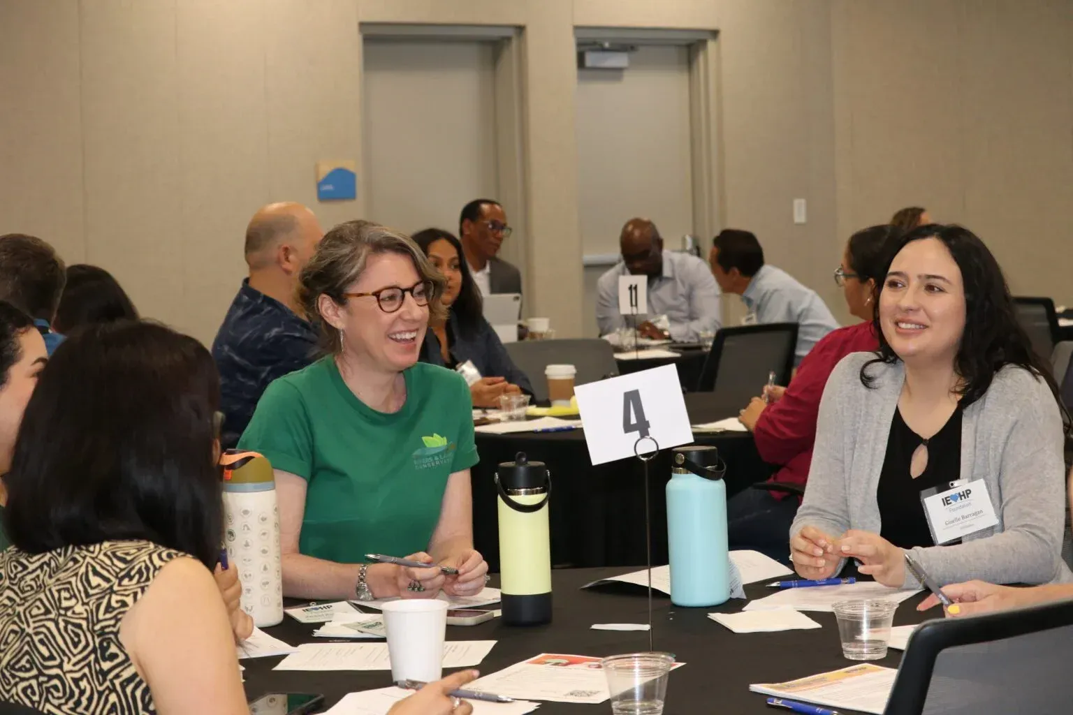 People seated at tables in a conference room, engaged in conversation.