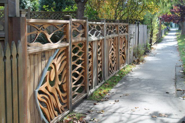 A wooden fence along a sidewalk with a design on it
