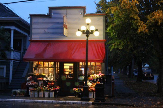 A store front with a red awning is lit up at night