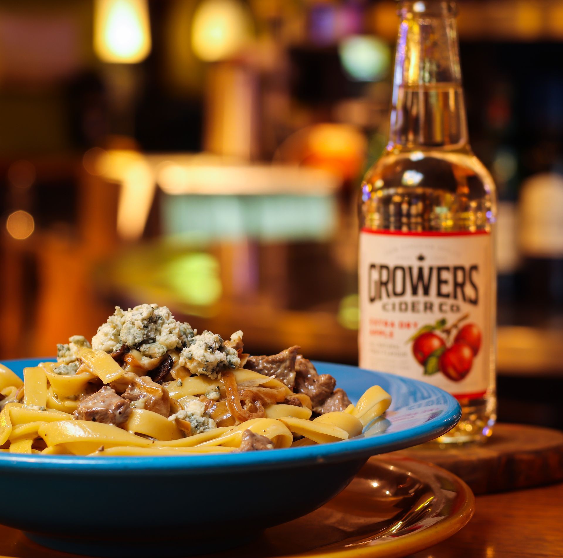 A bottle of growers cider sits next to a bowl of food