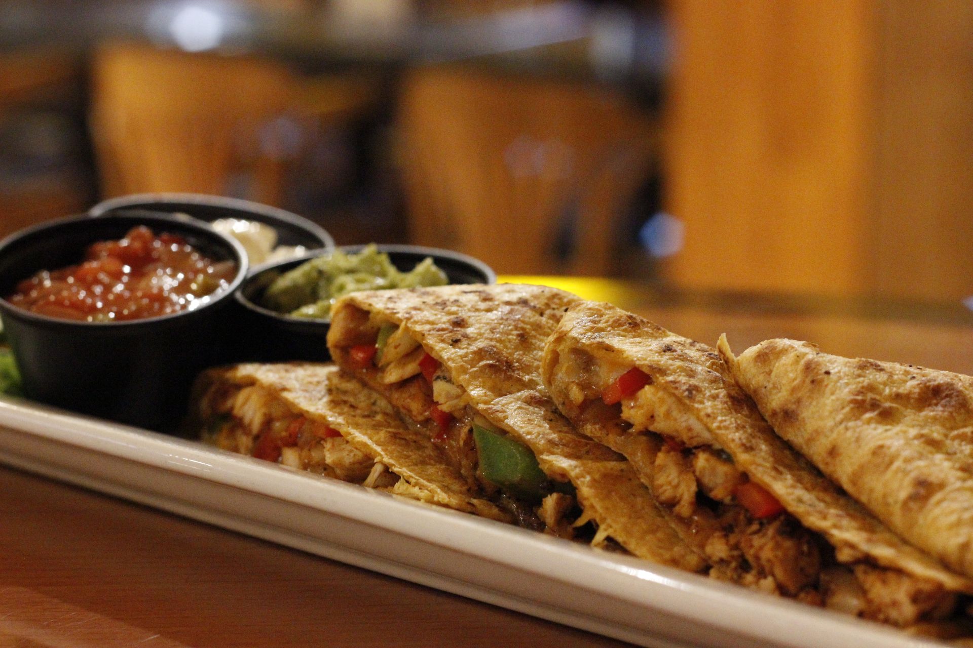 A white plate topped with quesadillas and salsa on a wooden table.