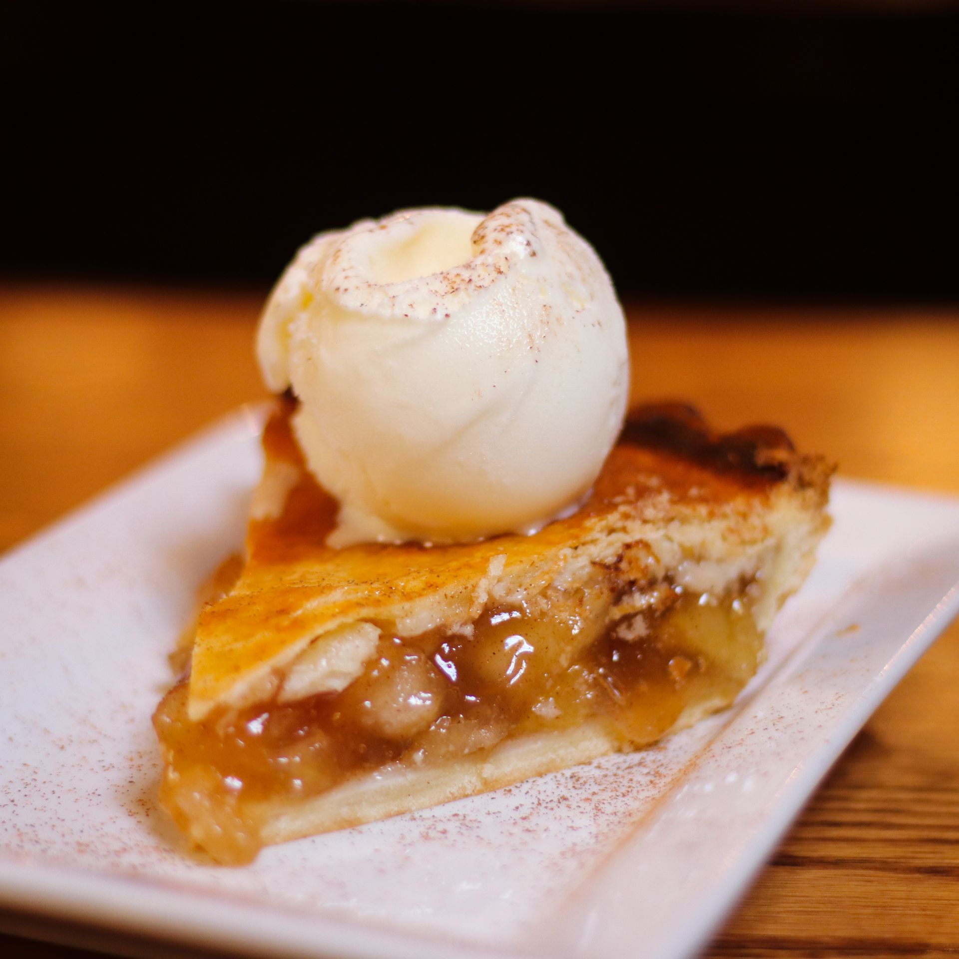 A slice of apple pie with a scoop of ice cream on top