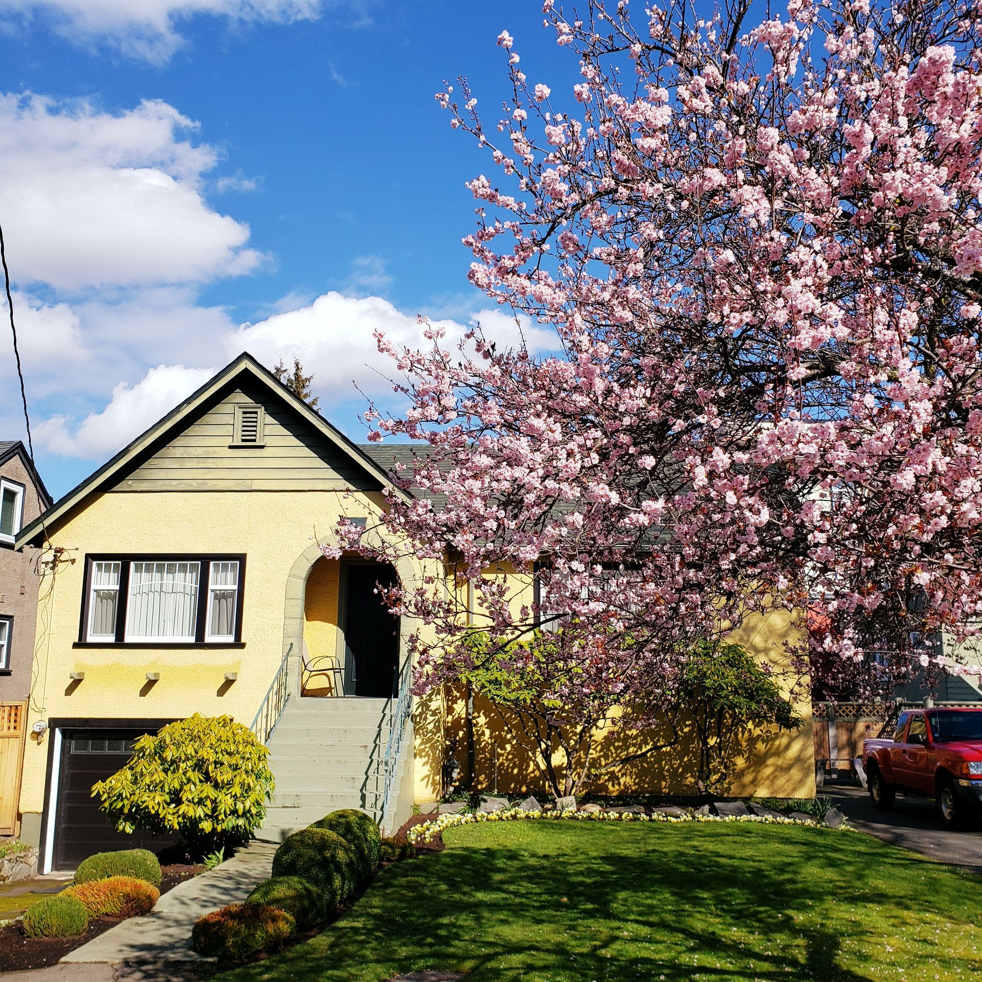 A yellow house with pink flowers in front of it