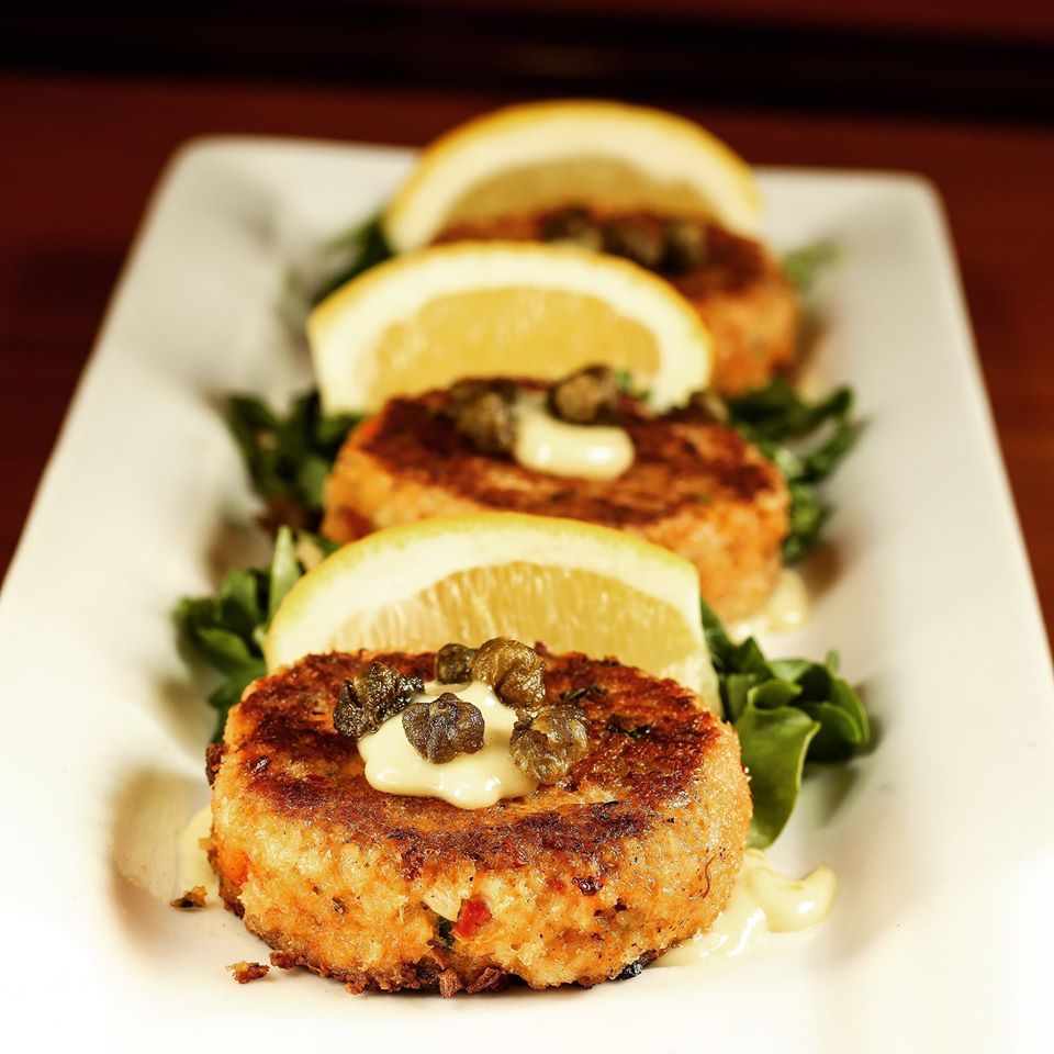 A white plate topped with crab cakes and lemon slices